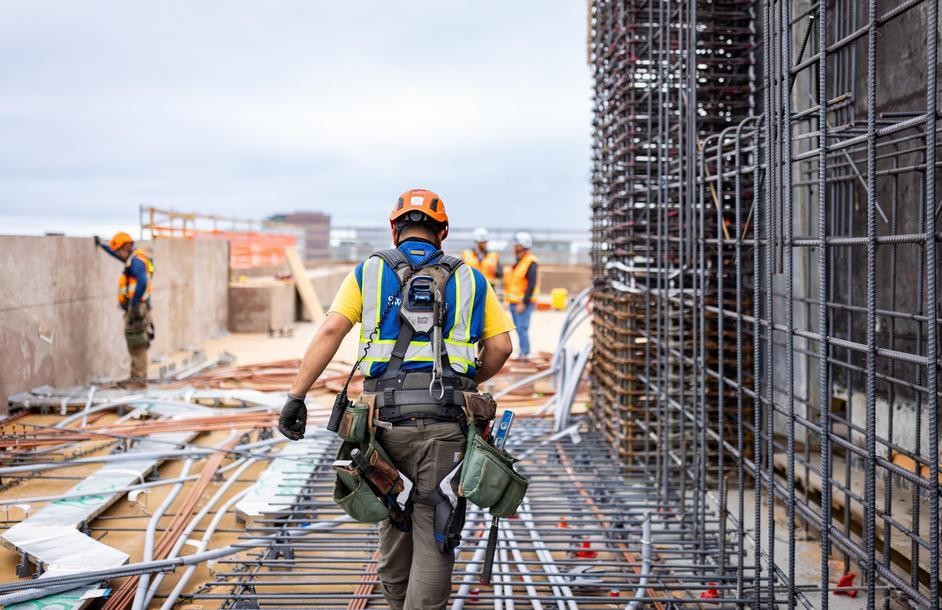 Worker crossing a reinforced concrete deck on an active commercial construction site